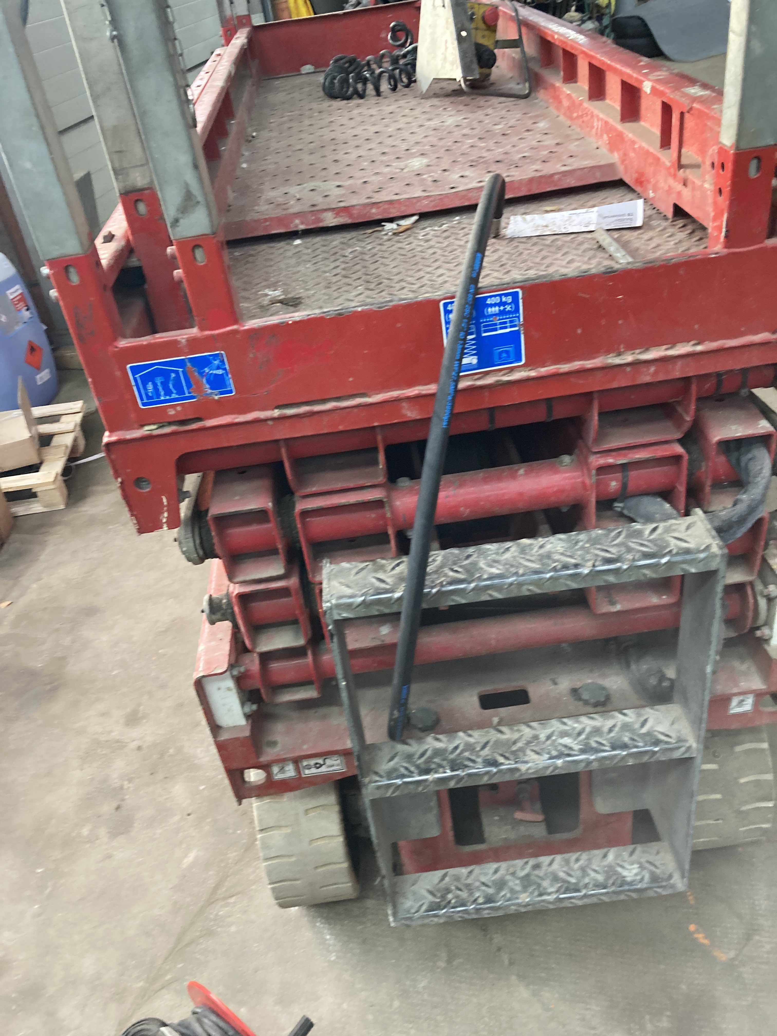 Rote Arbeitsbühne in einer Werkstatt, Detailansicht der Hebebühne mit Treppe