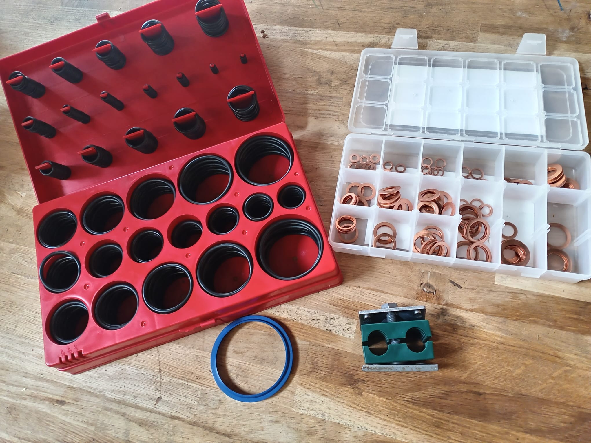 Sortiment von O-Ringen, Kupferdichtungen und Rohrschelle auf Holztisch