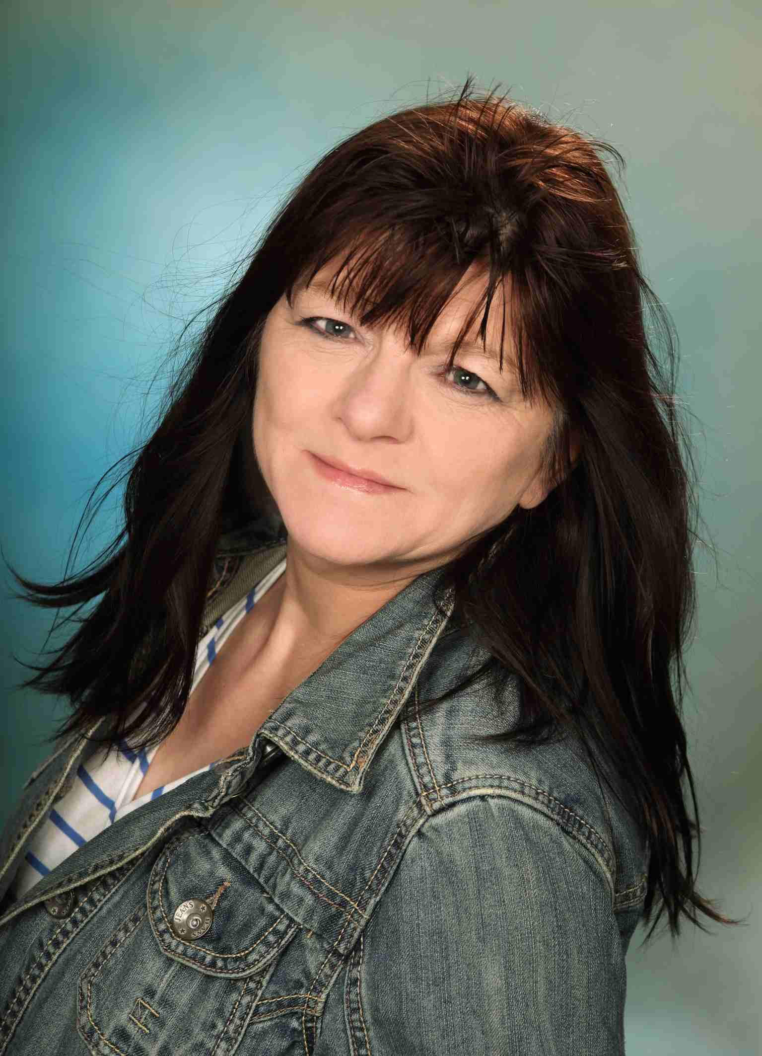 Porträt von Sonja Carlsson mit Jeansjacke vor blauem Hintergrund