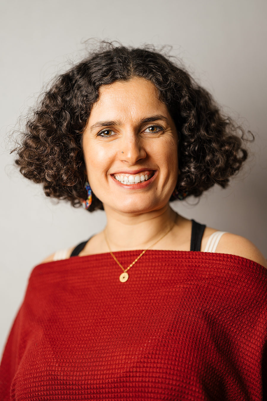 Portraitfoto von Deuretzbacher Kiran mit lockigen Haaren und rotem Oberteil