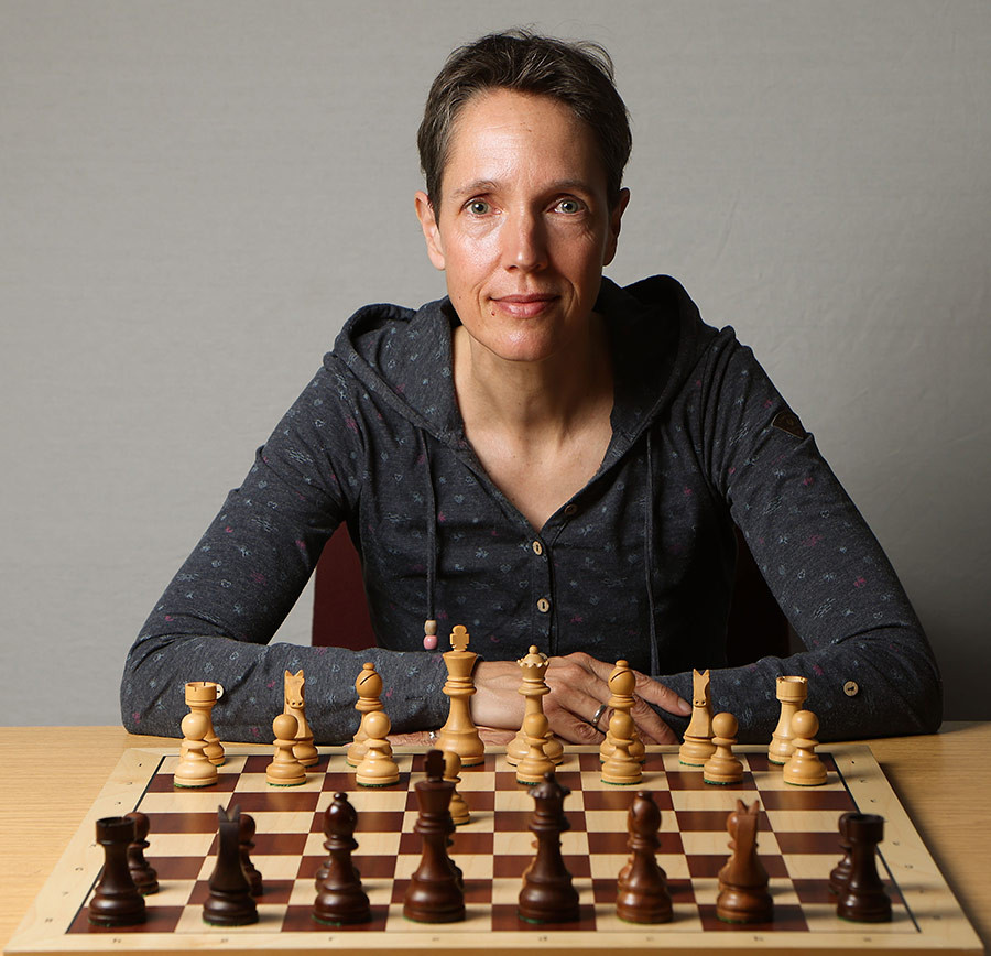 Silke Einacker sitzt an einem Schachbrett und bereitet sich auf eine Schachpartie vor