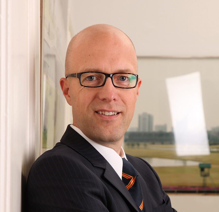 Eike Hovermann im Anzug vor einem Fenster mit Stadtblick