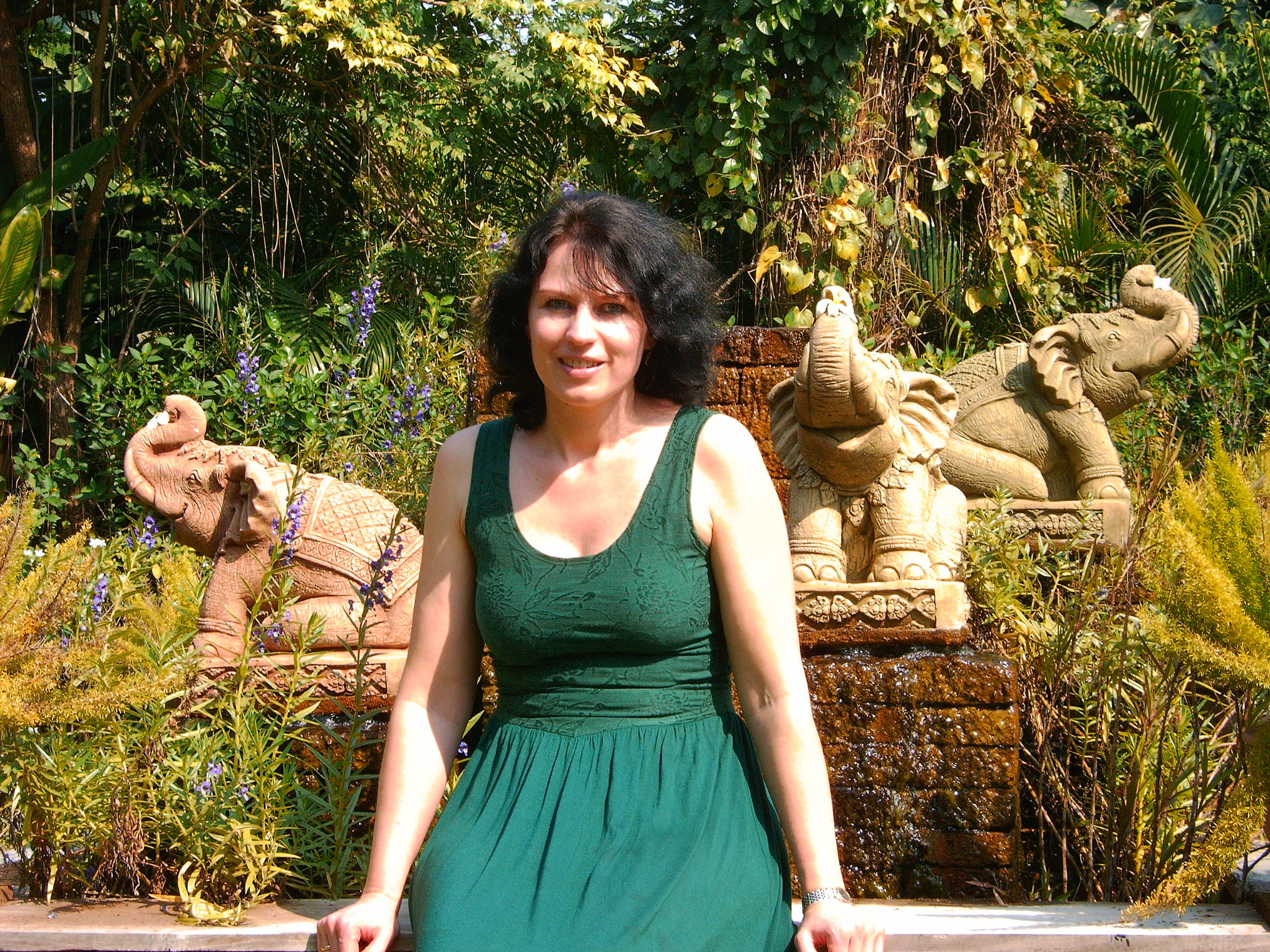 Zora Gienger sitzt vor dekorativen Elefanten-Statuen im Garten