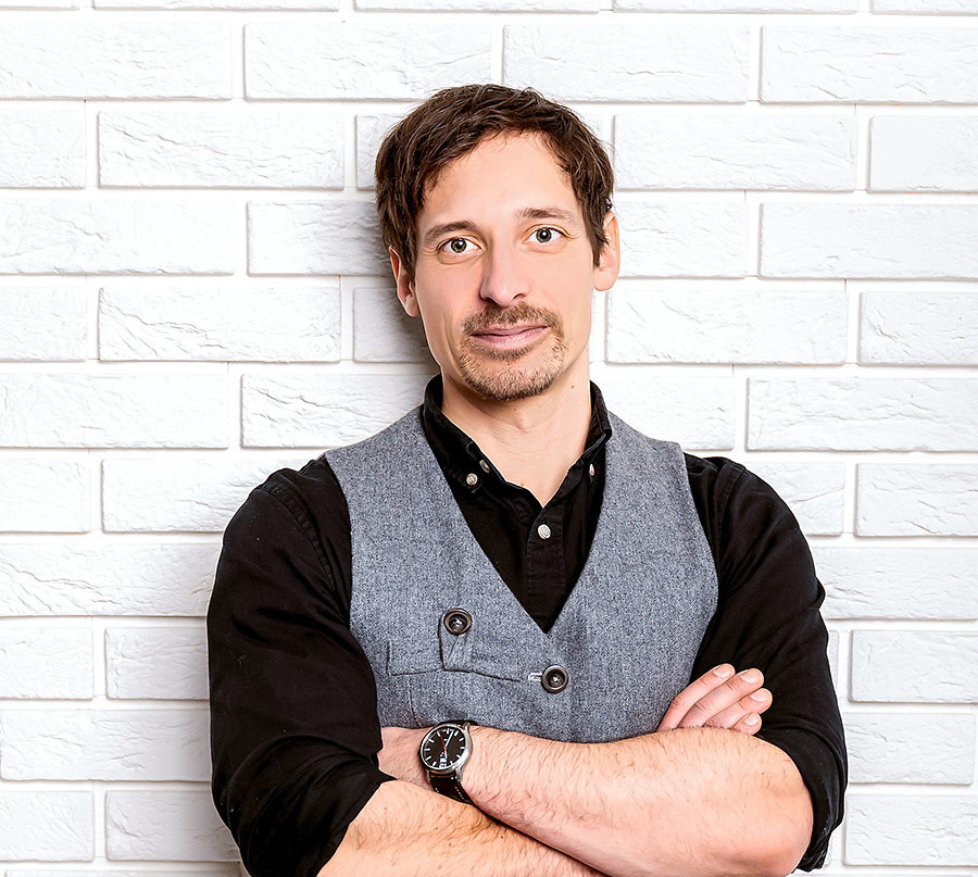 Porträt von Thomas Struppe vor weißer Backsteinwand mit verschränkten Armen