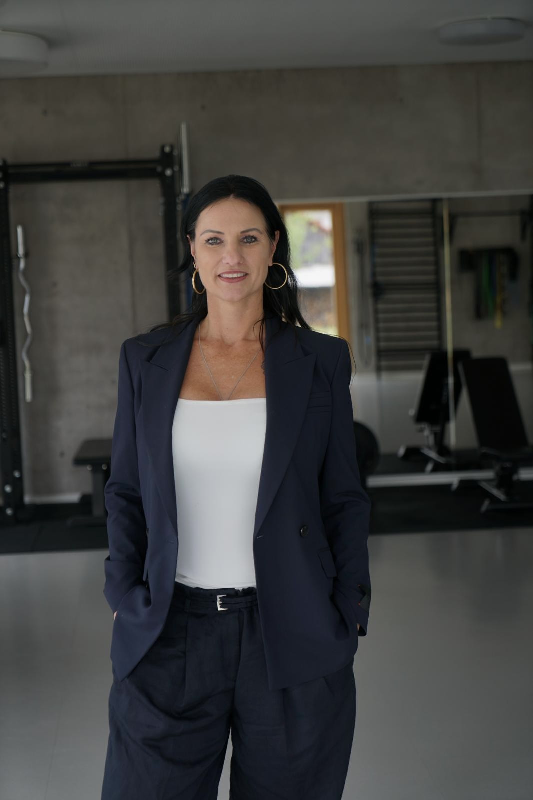 Kristin van der Meer in einem modernen Fitnessstudio mit dunklem Blazer
