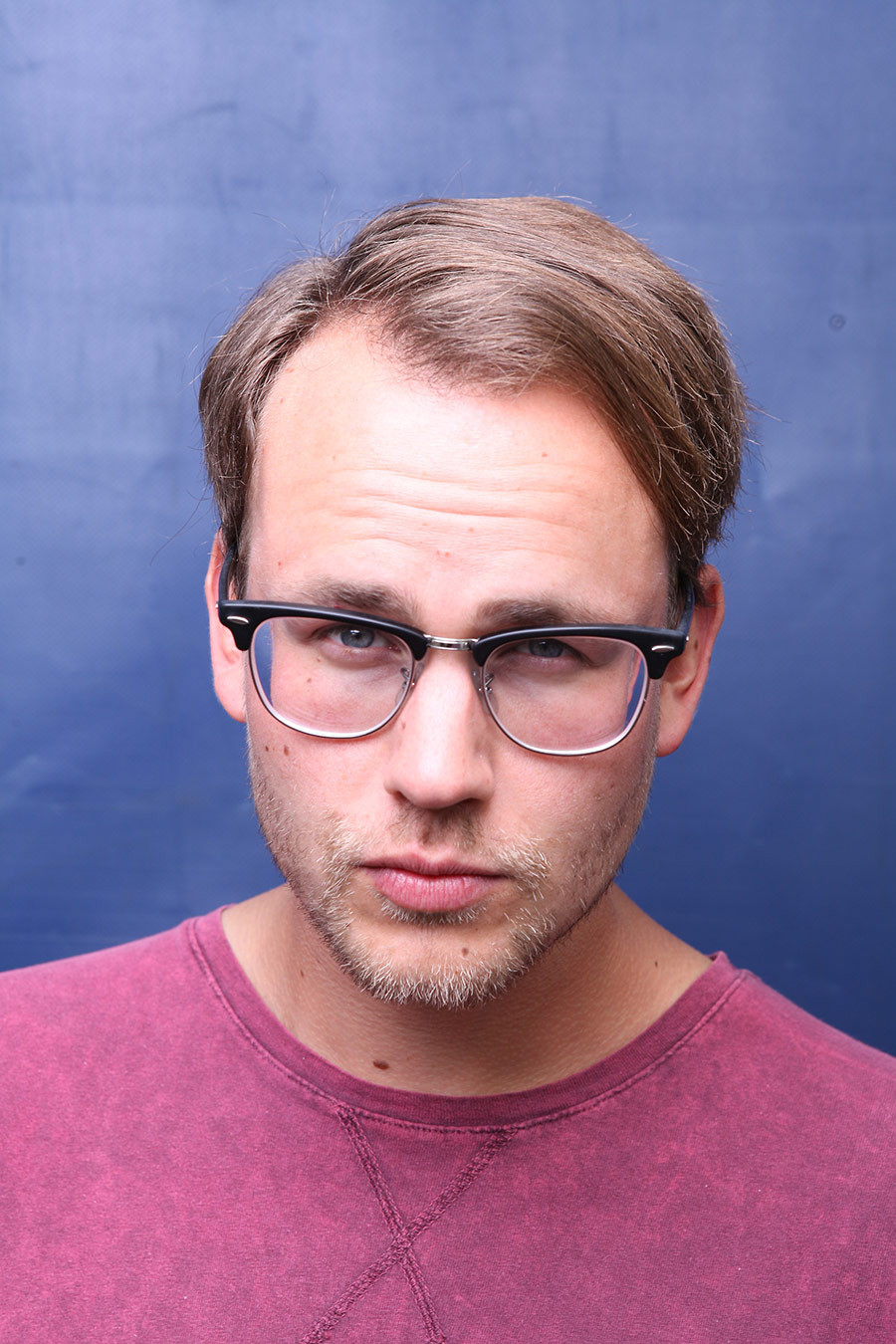 Portrait von Benjamin Breitmeier vor blauem Hintergrund