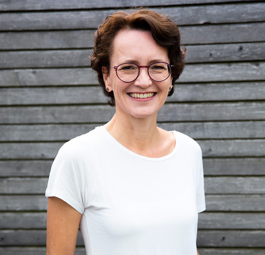 Porträtfoto von Eva Dragosits vor einer Holzfassade