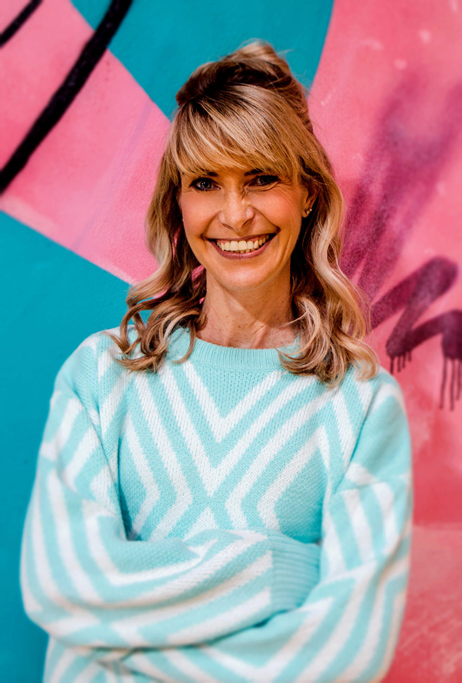 Anke Glassmeyer vor bunter Wand mit mintfarbenem Pullover