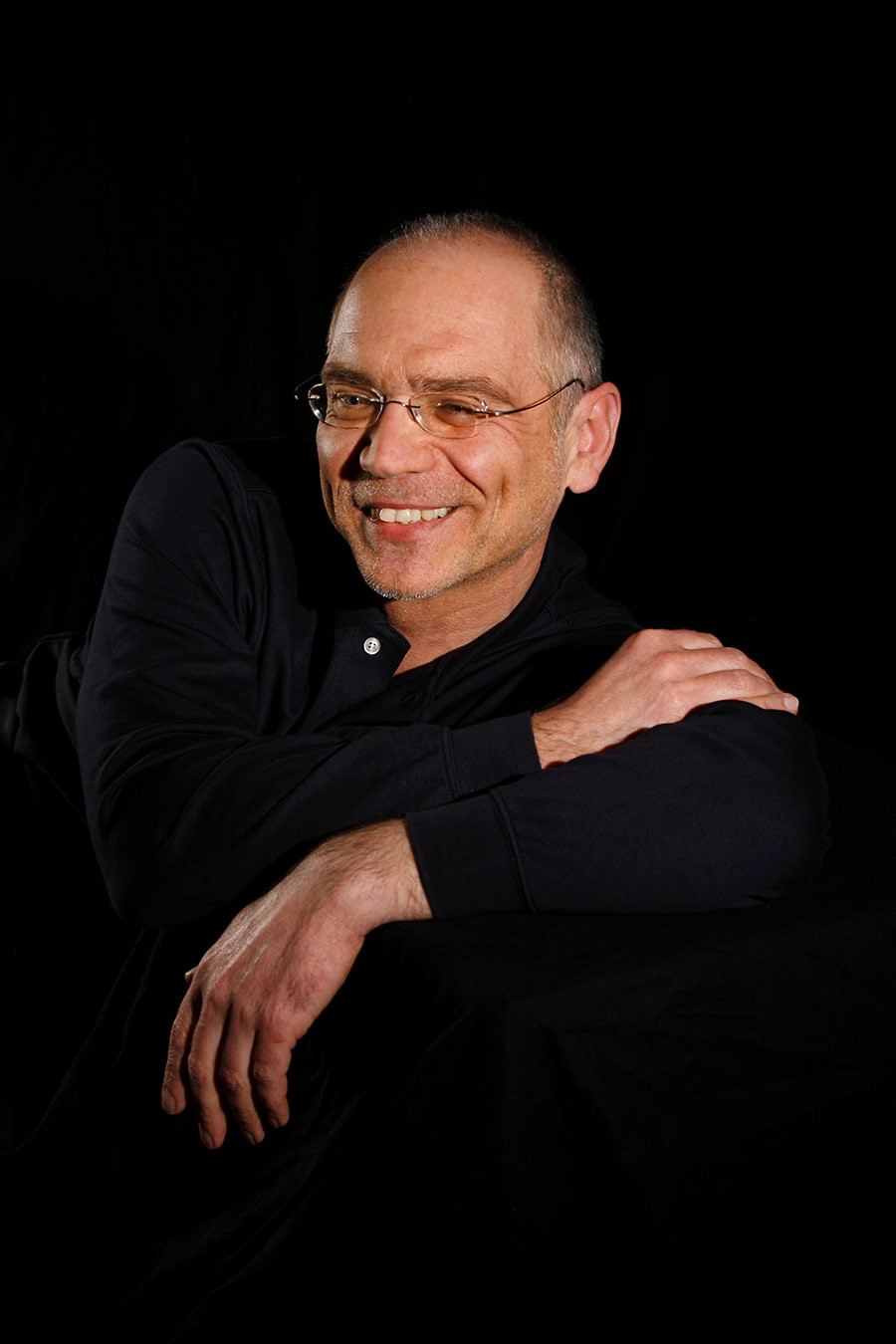 Porträtfoto von Uwe Hampel in dunkler Kleidung vor schwarzem Hintergrund