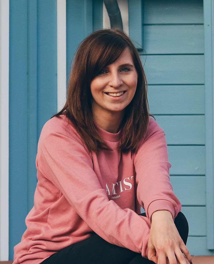 Sabrina Heinke vor blauem Hintergrund in rosa Pullover