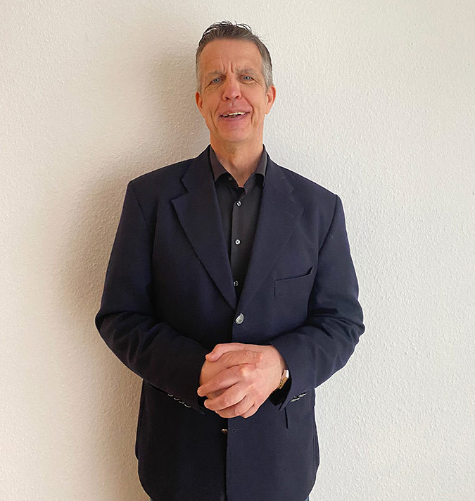 Porträt von Dr. Henning Hirsch im Anzug vor weißer Wand