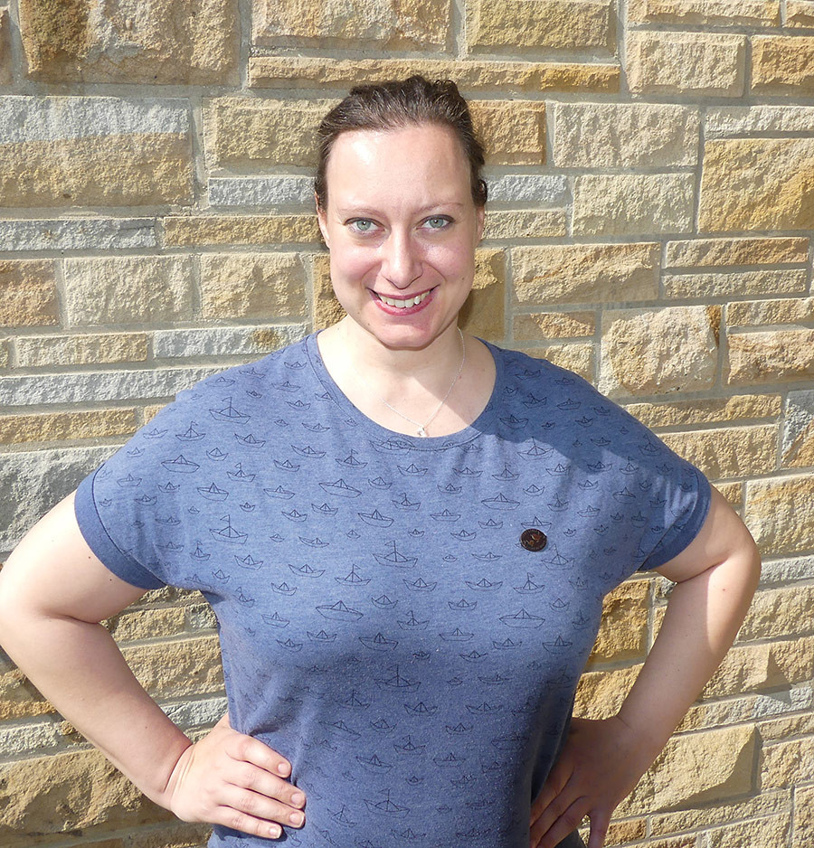 Frau mit blauem T-Shirt Mondstein Mira vor einer Steinwand