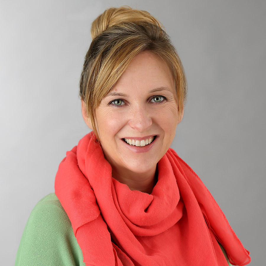 Portrait von Sara Zeitlmann mit rotem Schal und grünem Oberteil