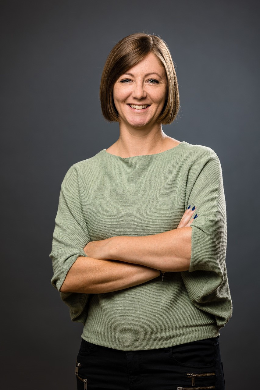 Portrait von Michele Liussi mit verschränkten Armen vor grauem Hintergrund