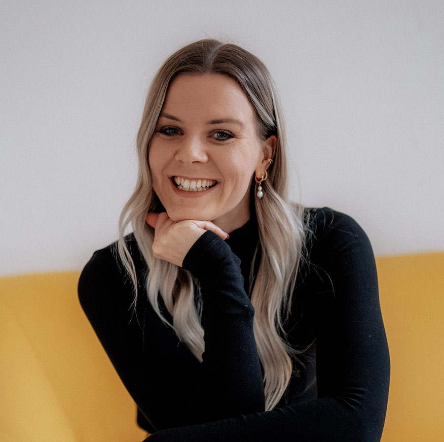Portrait von Svenja, Expertin für Kinderpädagogik, lächelnd auf einem gelben Sofa