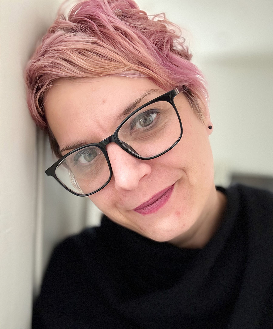 Portrait von Ramona Vetter mit Brille und kurzen, rosa Haaren