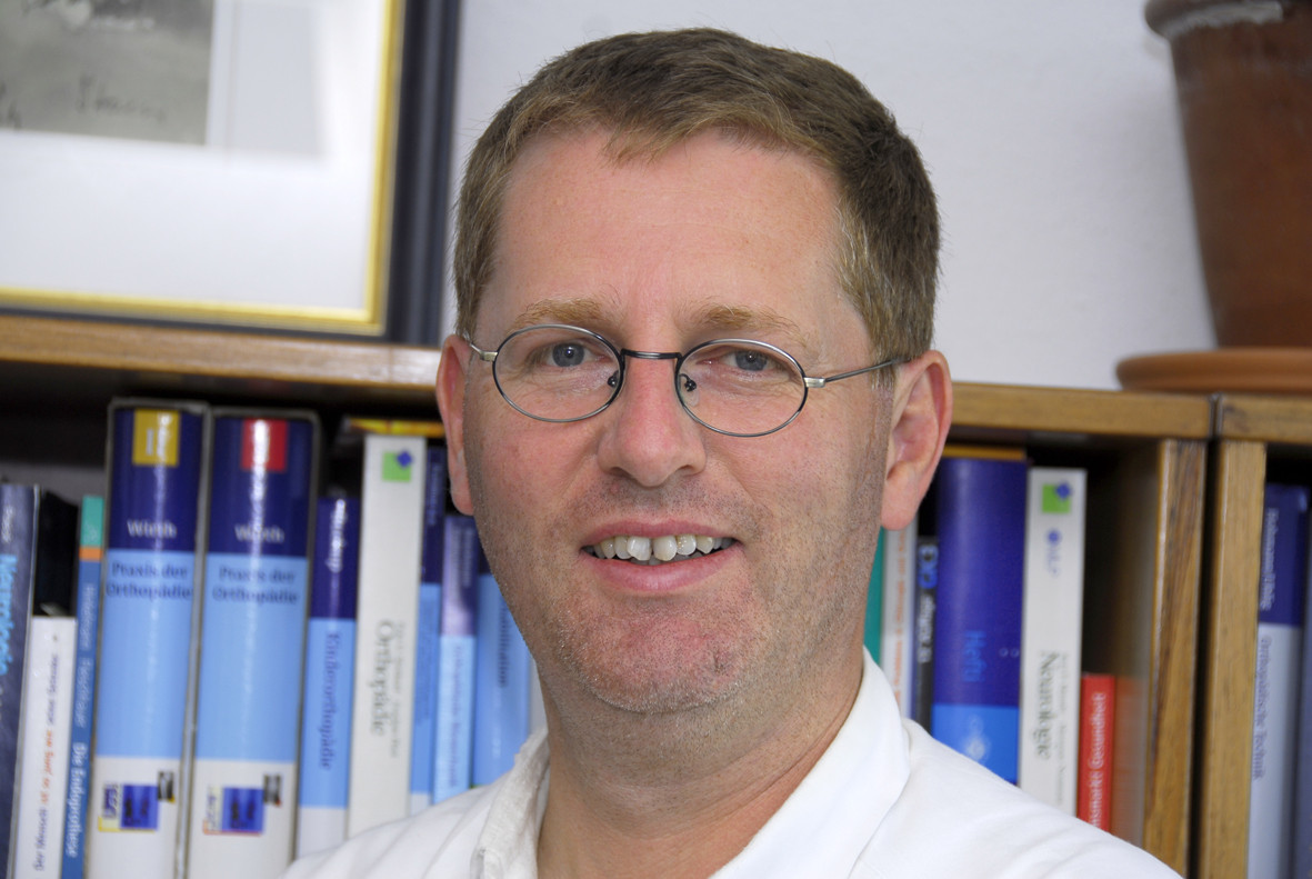 Portrait von Dr. med. Uwe Rueckert vor einem Bücherregal