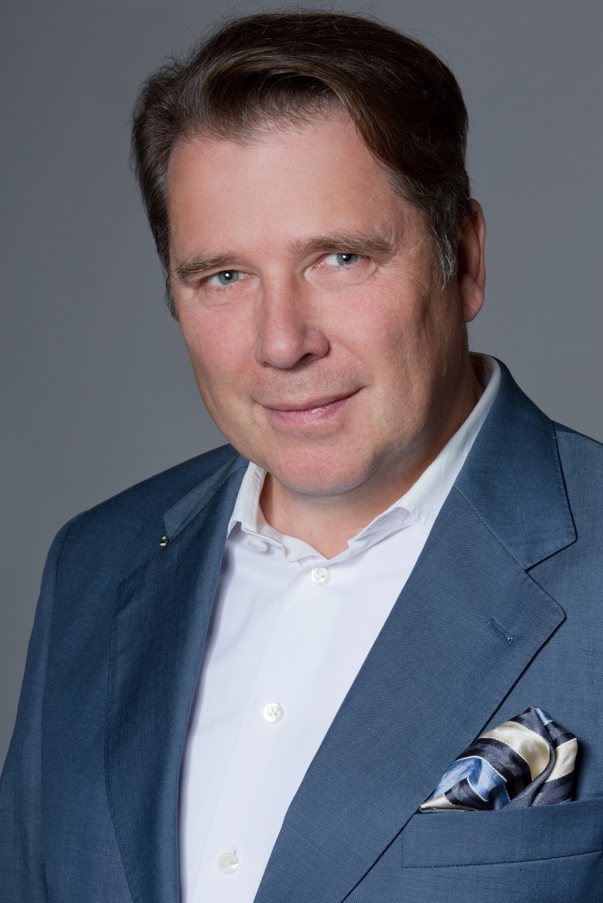 Portrait von Holger Westermann im Anzug vor grauem Hintergrund