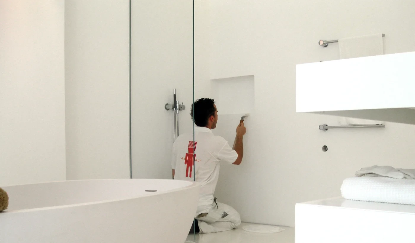 Handwerker gestaltet ein modernes, fugenloses Bad mit weißer Wand und Badewanne