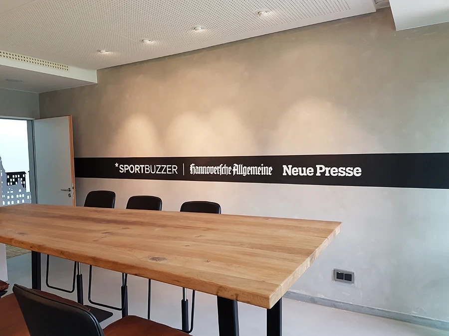 Besprechungsraum mit Wandgestaltung und Logos von Sportbuzzer, Hannoversche Allgemeine und Neue Presse als Referenz von Farbgestalt