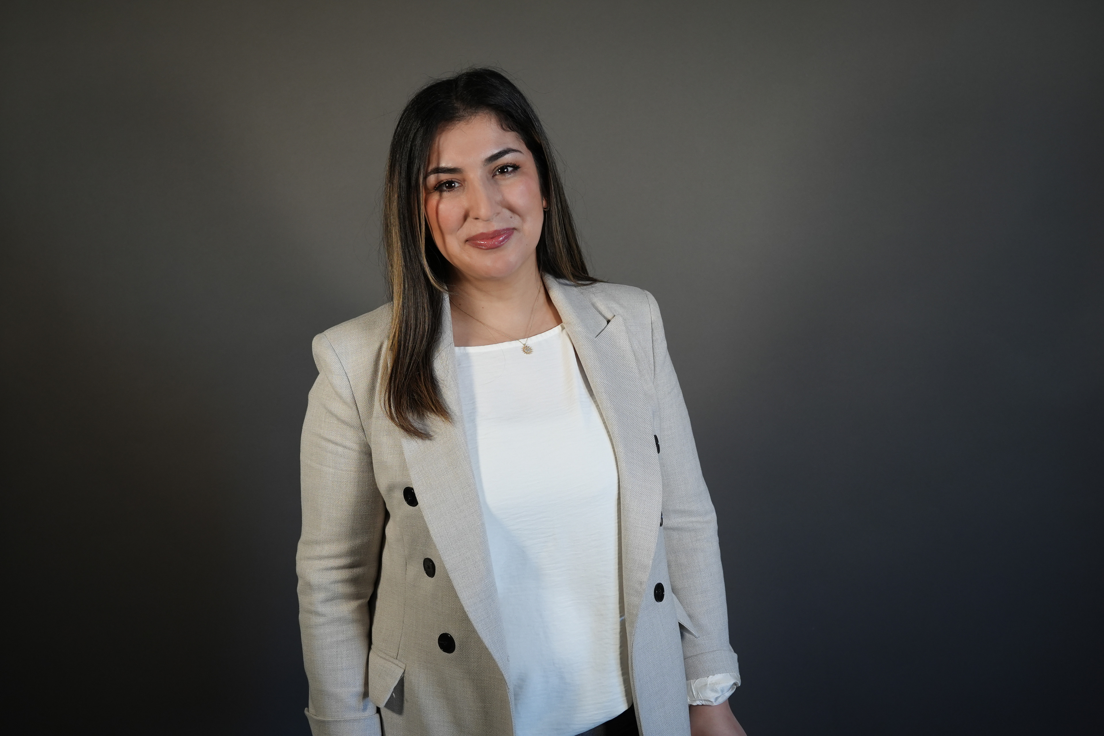Frau im Business-Outfit mit beigem Blazer vor neutralem Hintergrund