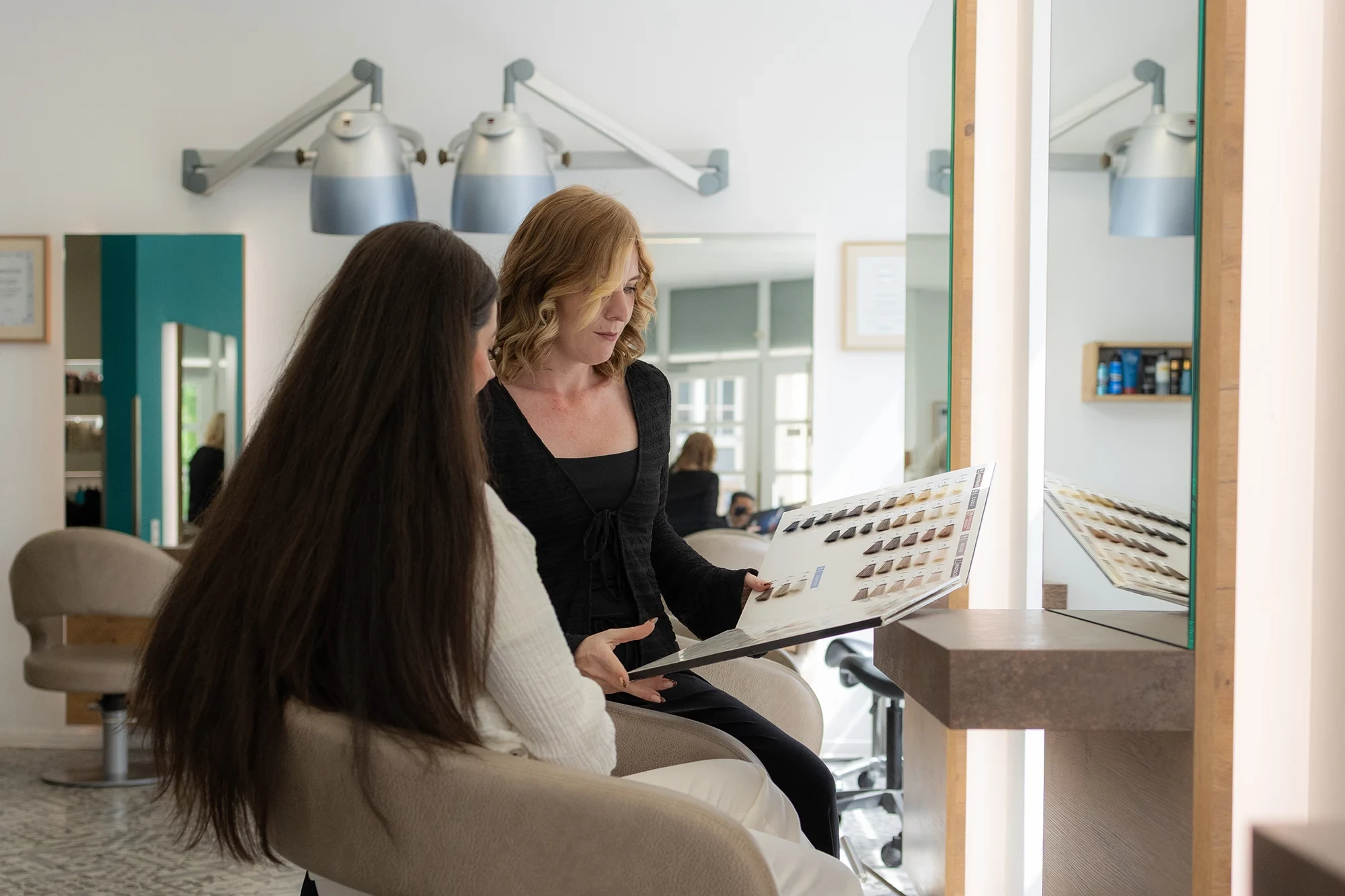 Zwei Frauen bei der Friseurberatung im Salon, Auswahl von Haarfarben am Friseurtisch