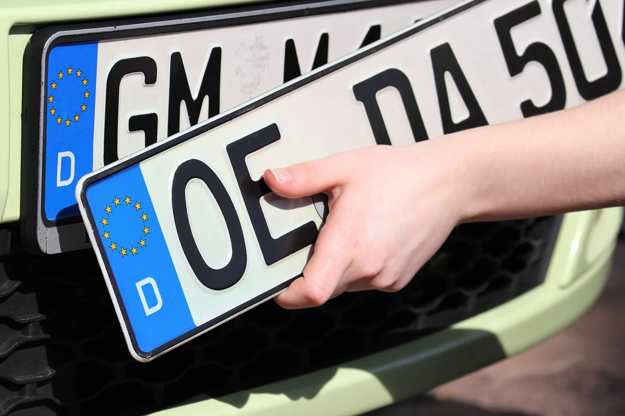 Deutsches Kfz-Kennzeichen wird am Auto angebracht