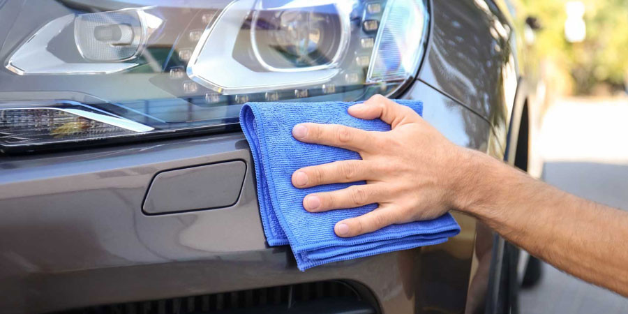 Scheinwerfer-Intensivreinigung bei Autoservice Velten in Bruchsal und Heidelberg – Hand reinigt Autoscheinwerfer mit Mikrofasertuch
