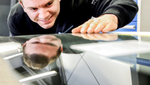 Mann prüft reflektierende Oberfläche auf Qualität