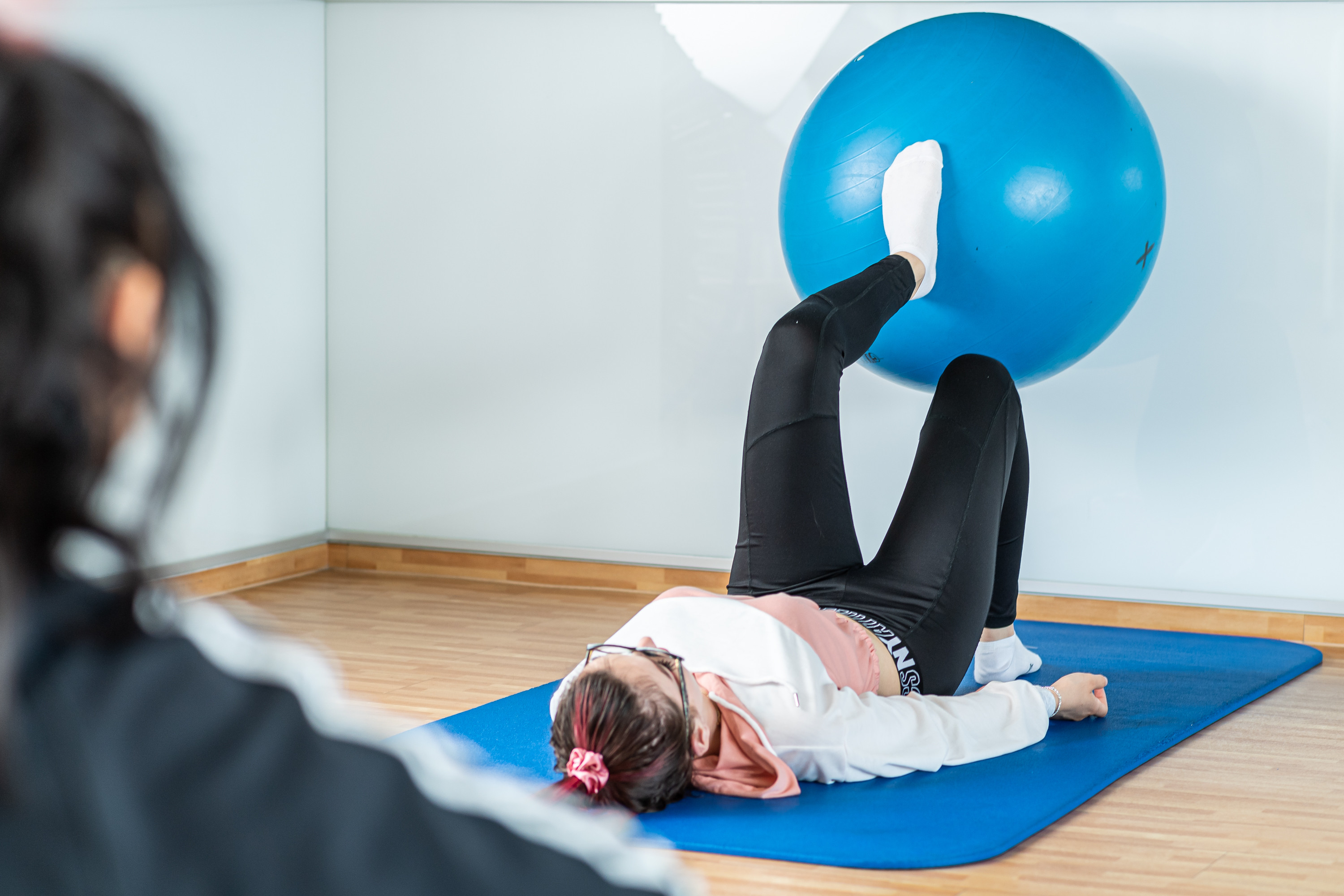 Reha Ball Übung: Frau macht Physiotherapie mit Gymnastikball auf Matte