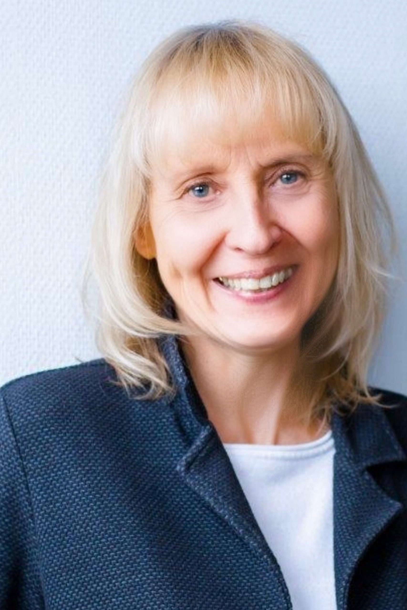 Porträt einer Frau namens Trixi, lächelnd vor hellem Hintergrund