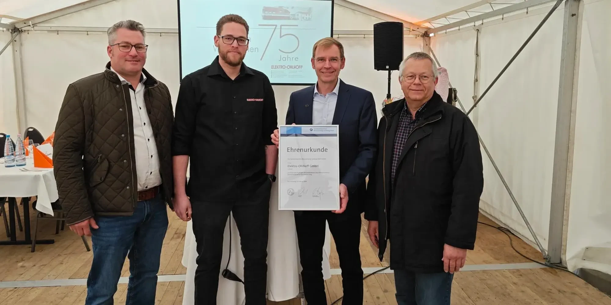 Die Elektro Ohlhoff GmbH feiert 75-jähriges Jubiläum – Gruppenfoto mit Ehrenurkunde bei der Jubiläumsfeier.