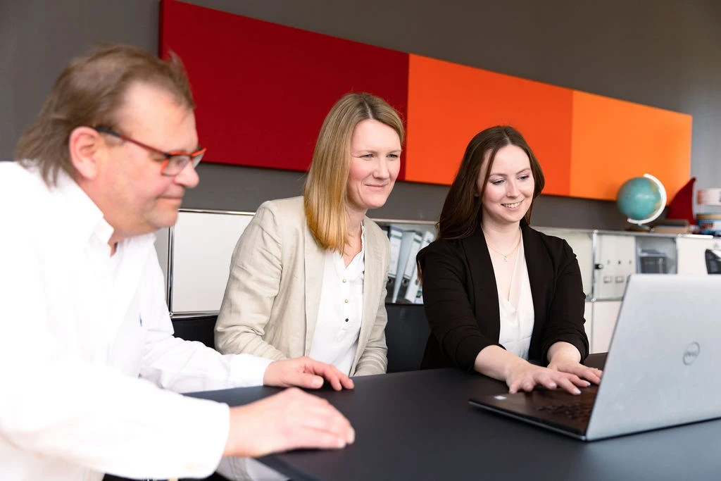 Team arbeitet gemeinsam am Laptop im Büro