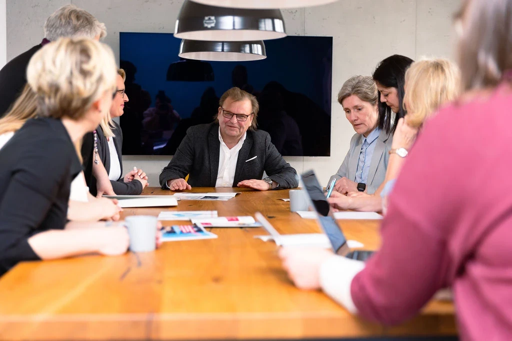 Großes Teammeeting mit mehreren Personen an einem Konferenztisch