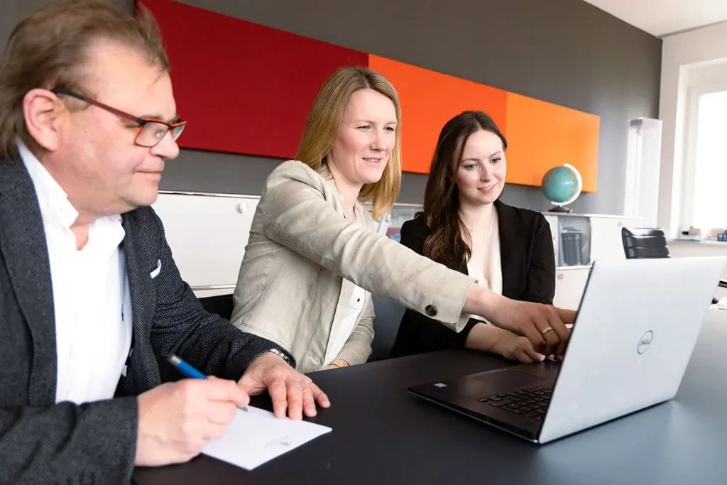 Team arbeitet gemeinsam am Laptop im Büro