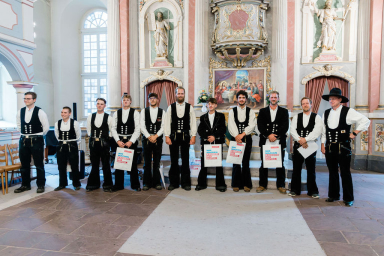Zimmerer-Innung: Zimmerer in traditioneller Zunftkleidung bei einer Veranstaltung in der Kirche Gruppenfoto von Zimmerern der Zimmerer-Innung in traditioneller Zunftkleidung in einer Kirche