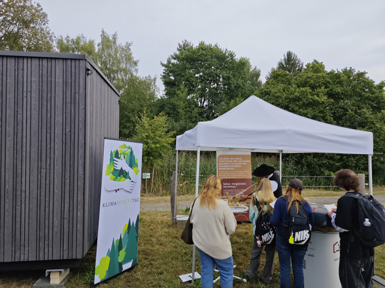 Zimmerer am Infostand auf dem Klimaschutztag informiert über nachhaltigen Holzbau Zimmerer informiert Besucher auf dem Klimaschutztag an einem Infostand zum nachhaltigen Holzbau