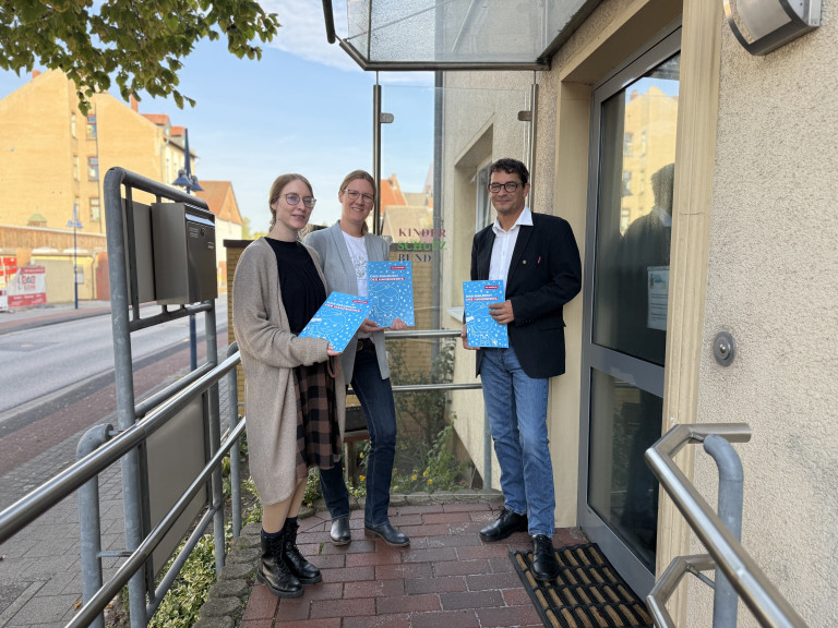 Drei Personen mit Broschüren vor dem Kinderschutzbund Peine Drei Personen vor dem Eingang des Kinderschutzbundes Peine mit Informationsbroschüren in der Hand