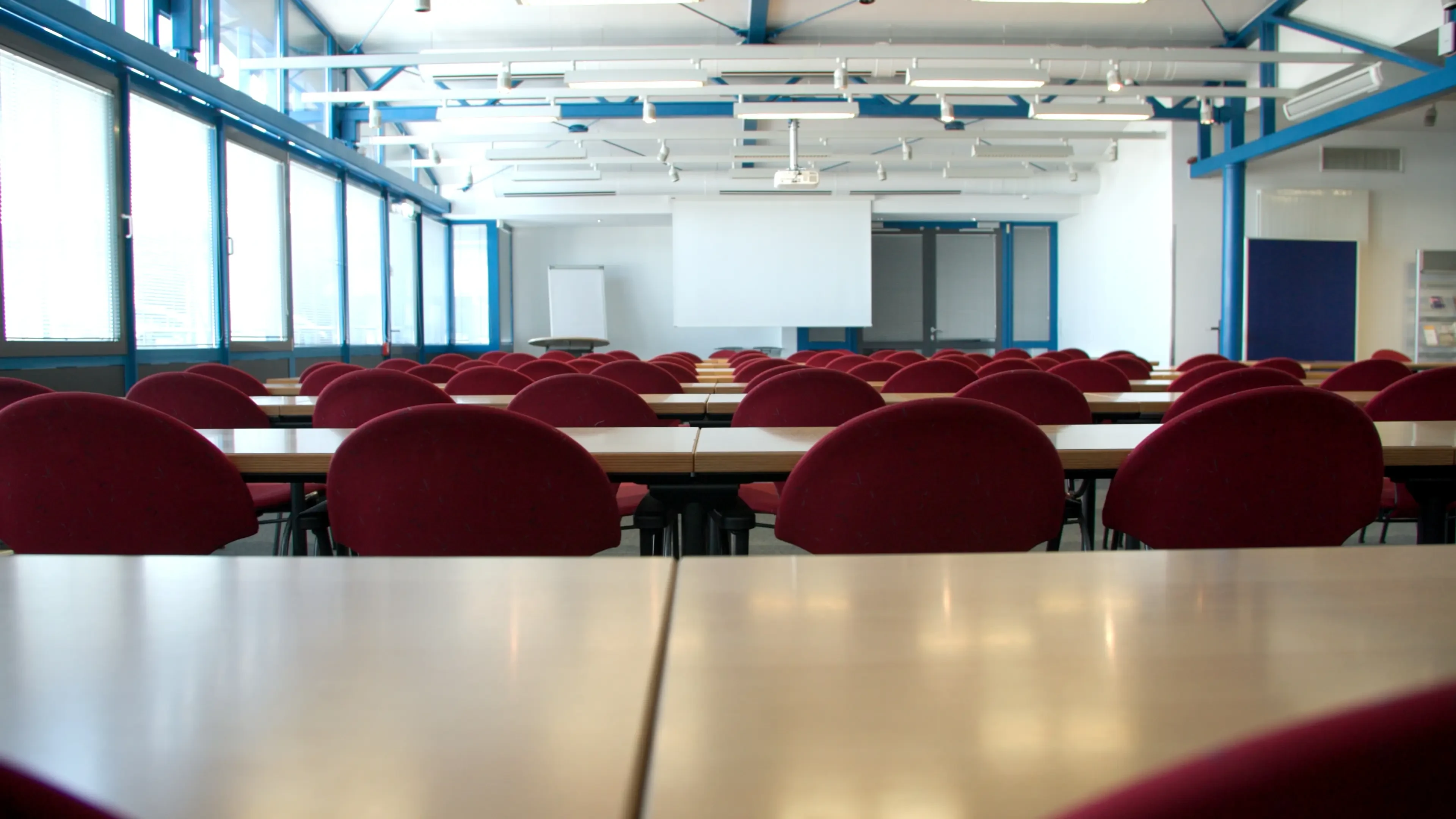 Moderner Konferenzraum mit vielen roten Stühlen und Präsentationsfläche