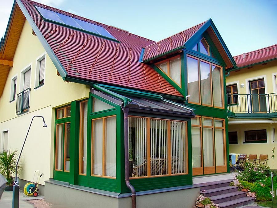 Moderner Wintergarten nachher an Einfamilienhaus mit grünen Rahmen und großen Glasflächen