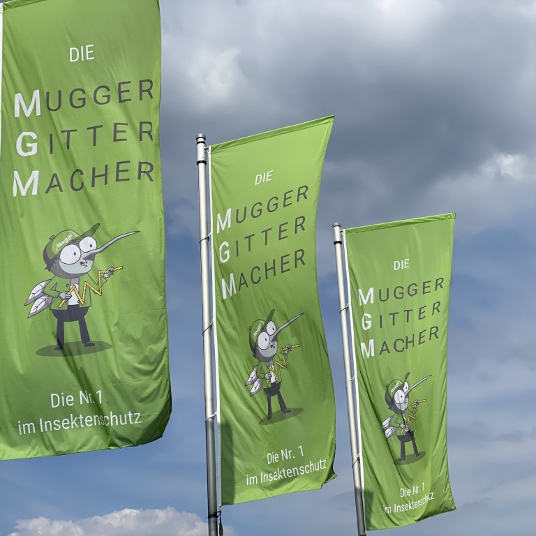 Fahnen der Mugger Gitter Macher mit Slogan Die Nr. 1 im Insektenschutz vor bewölktem Himmel