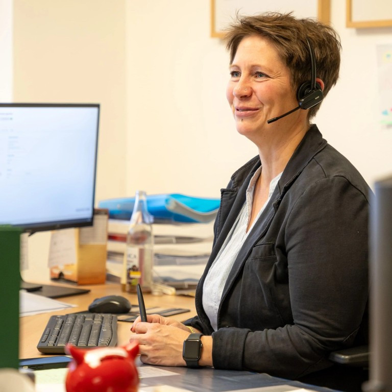 Mitarbeiterin im Büro bei Muggergittermacher Baldham am Computer mit Headset