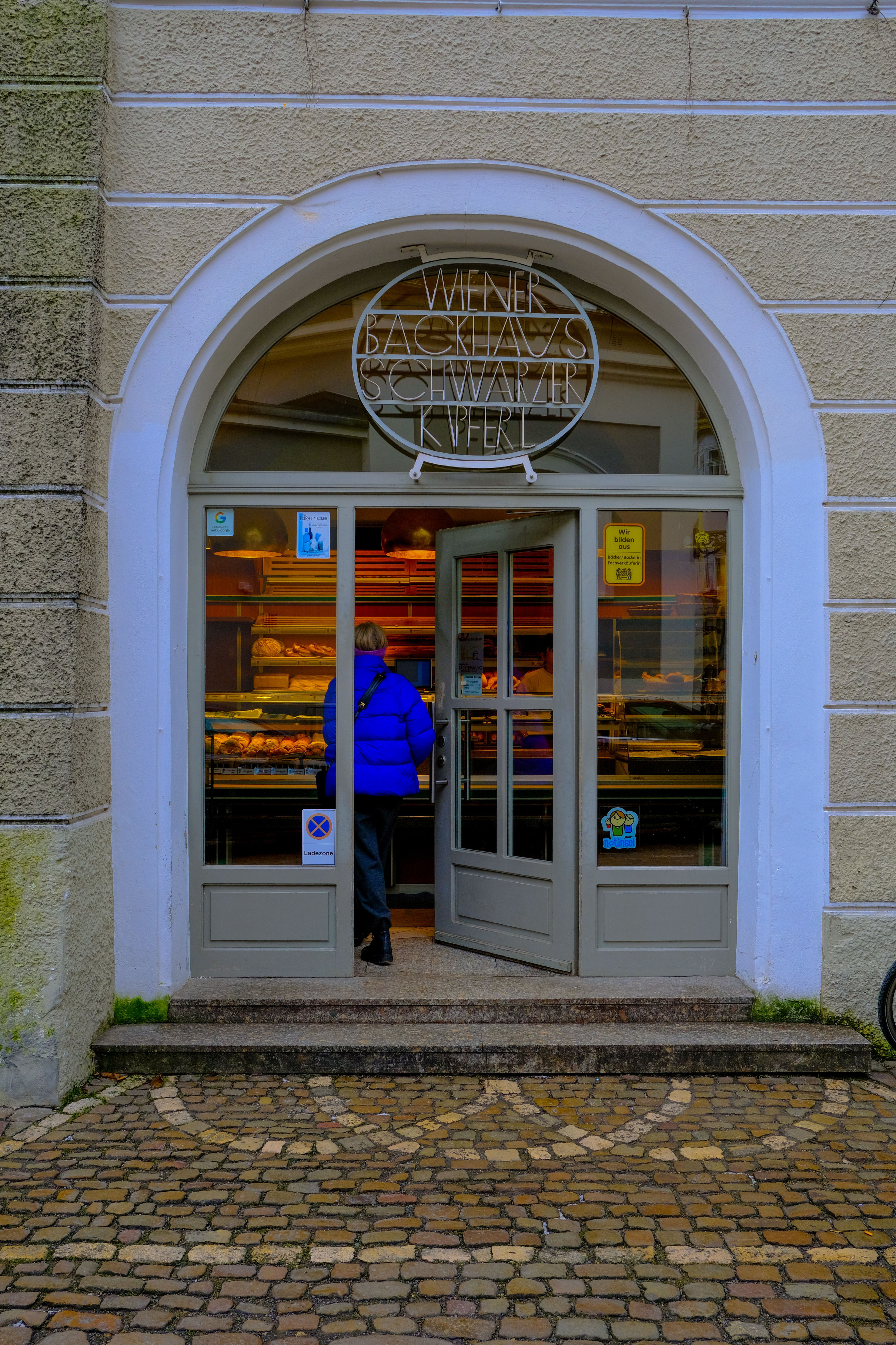 Eingang einer Bäckerei mit einem Kunden vor der Theke