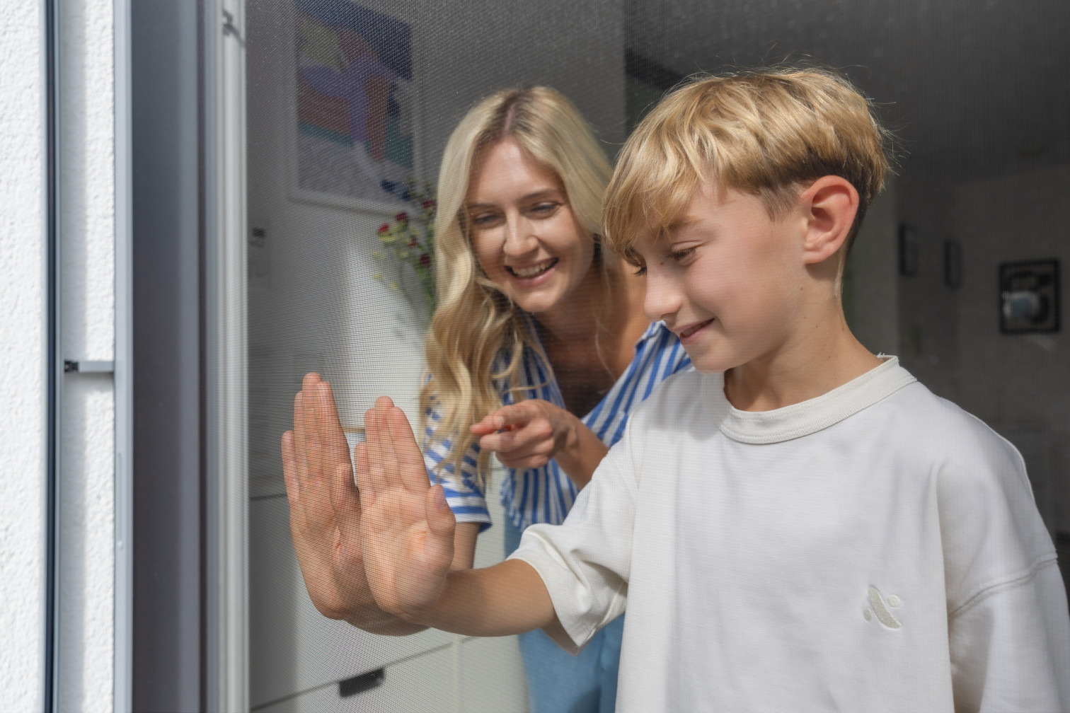 Frau und Junge testen gemeinsam ein Fliegengitter an einer Tür