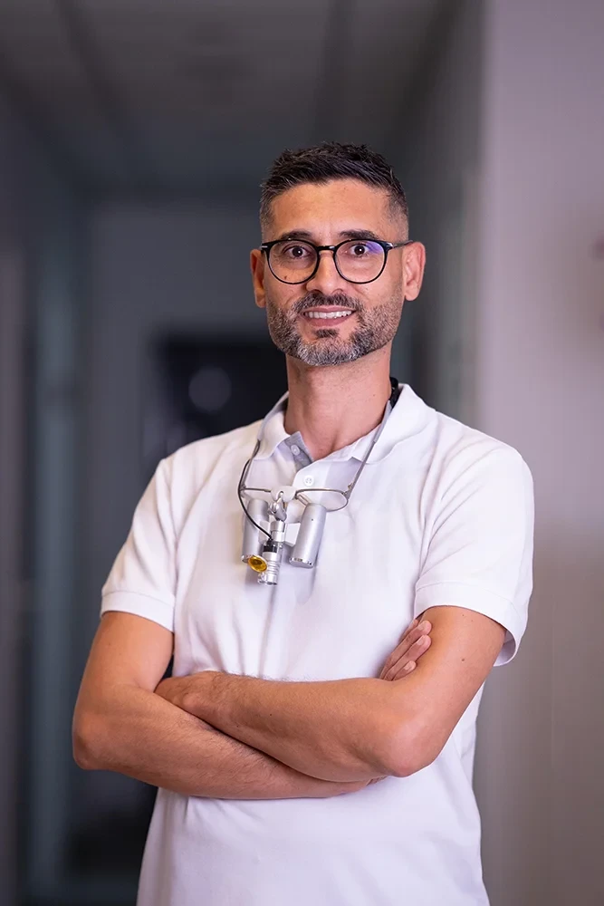 Porträt von Dr. Khalil mit Zahnarztlupe in moderner Praxis