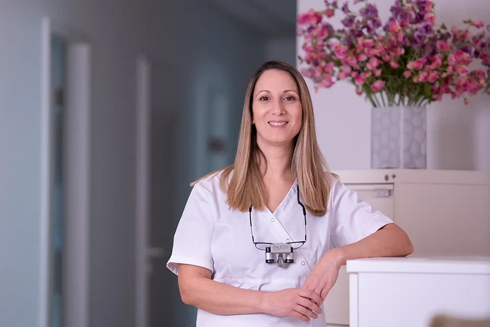 Dr. Jbara alleine in Praxisumgebung mit weißem Kittel und Lupenbrille