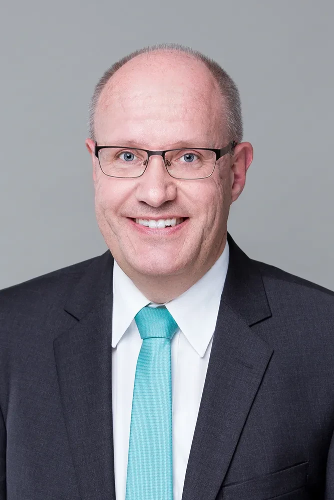 Porträt von Klaus Peineke im Anzug mit türkiser Krawatte