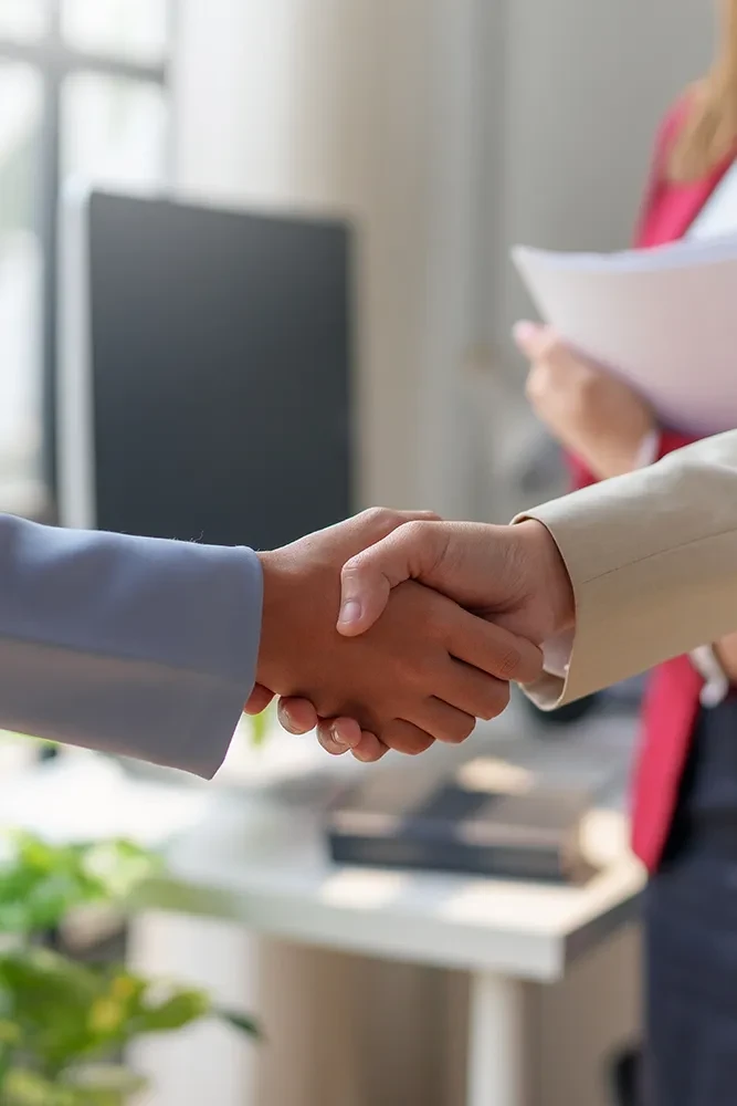 Zwei Personen geben sich im Büo die Hand