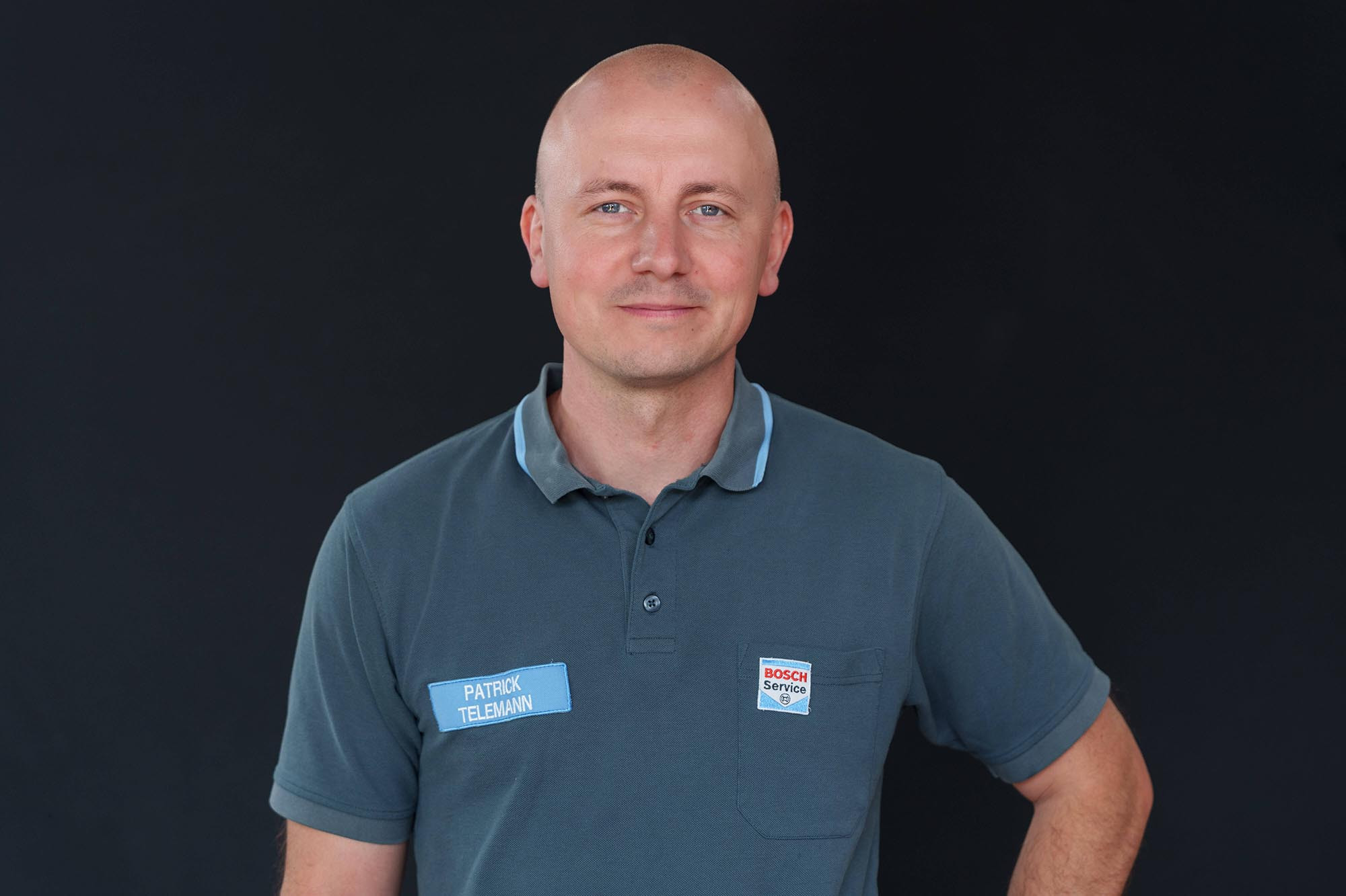 Mitarbeiter von Bosch Service mit Namensschild Patrick Telemann vor schwarzem Hintergrund