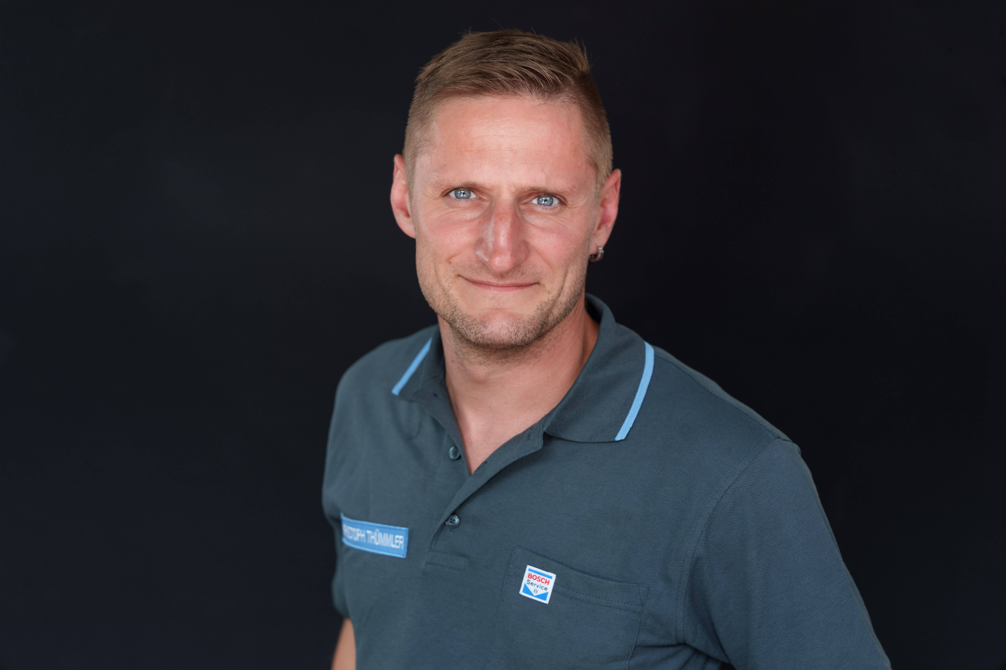 Porträt eines lächelnden Mannes im Bosch Service Shirt vor schwarzem Hintergrund